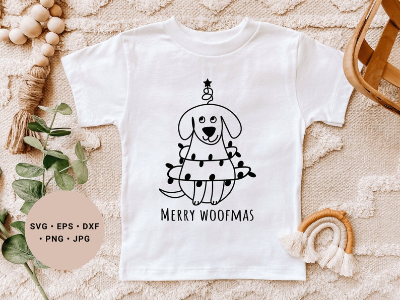 May include: White t-shirt with a black and white illustration of a dog wearing a Christmas tree costume. The text "Merry Woofmas" is printed below the illustration.