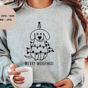 May include: A gray sweatshirt with a black and white illustration of a dog wearing Christmas lights. The text "Merry Woofmas" is printed below the illustration.