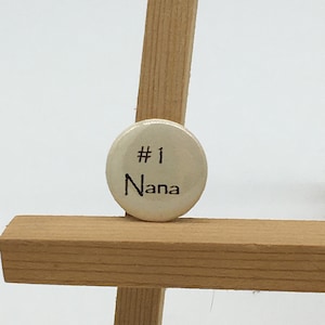 May include: A white button with black text that reads "#1 Nana".