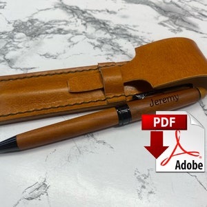 Op de afbeelding: Een bruine leren pennenhouder met een gestikte rand en een klep sluiting. De houder is gepersonaliseerd met de naam "Jeremy" en wordt getoond met een houten pen met een zwarte punt.