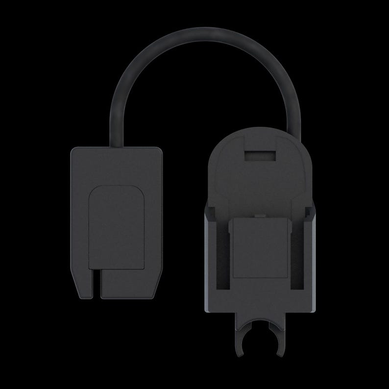 May include: A black dental X-ray sensor holder with a connecting cable. The holder has two main components: a rectangular piece and a larger piece with a curved bottom and a clip. The background is black.