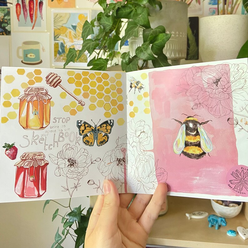 K&ouml;nnte beinhalten: Offenes Skizzenbuch mit Aquarellillustrationen von Honigt&ouml;pfen, einem Schmetterling, einer Biene und Blumen. Die linke Seite zeigt einen Honigl&ouml;ffel und ein Wabenmuster. Der Text auf der linken Seite lautet "STOP bring to life your Sketchbook".