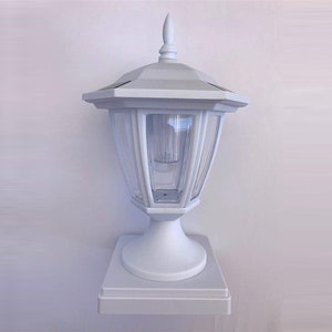 May include: White solar powered post cap light with a clear glass lantern and a square base.