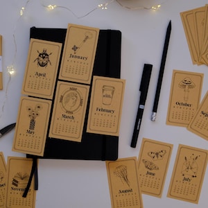 Set de pegatinas de calendario 2026 (12 meses) con ilustración lineal. Pegatinas para agenda, bullet journal, calendario mensual.