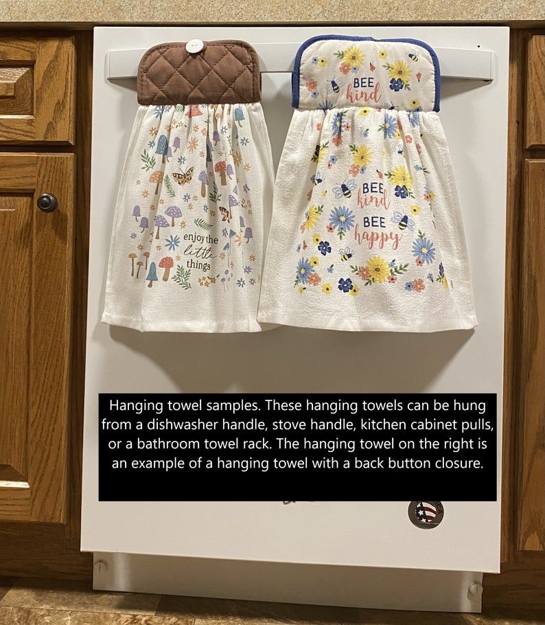 May include: Two hanging kitchen towels. One features a brown quilted top with a button, and a white towel with colorful mushrooms, butterflies, and the text "enjoy the little things." The other has a blue-trimmed top with flowers and the text "Bee kind Bee happy."
