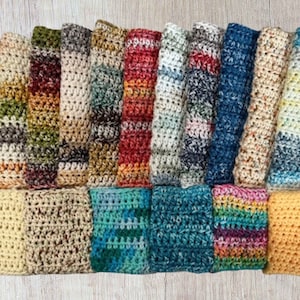 May include: A collection of 18 crocheted dishcloths in various colors and patterns, including brown, beige, green, blue, orange, yellow, and white.
