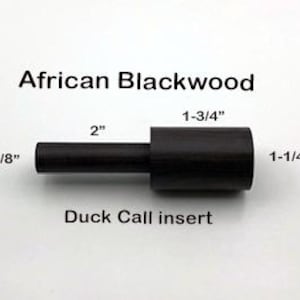 May include: A black wooden duck call insert made from African Blackwood. The insert is 1-3/4 inches long, 1-1/4 inches wide, and 5/8 inches thick.