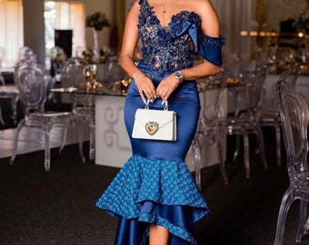 May include: A woman wearing a blue and white dress with a lace bodice and a ruffled skirt. She is holding a white handbag with a heart-shaped clasp.