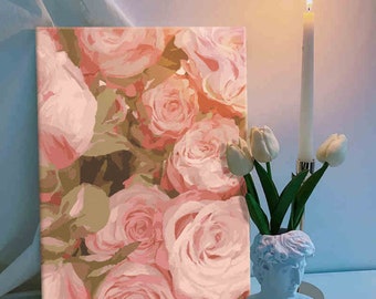 May include: A rectangular canvas print featuring a dense pattern of soft pink and peach roses. Beside the canvas stands a light blue bust-shaped vase holding three white tulips, accompanied by a tall, slender white candle in a metal holder.