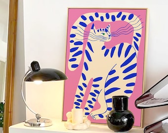 Könnte beinhalten: Ein rechteckiger gerahmter Wandkunstdruck, der eine stilisierte cremefarbene Katze mit kräftigen blauen Streifen vor einem leuchtend rosa Hintergrund zeigt. Die Katze hat lange, gewellte blaue Schnurrhaare und ein grünes Auge im flachen Grafikstil.