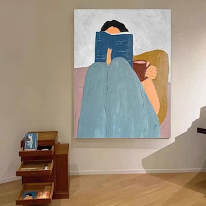 K&ouml;nnte beinhalten: Abstrakte Malerei einer Person, die ein blaues Buch liest und einen braunen Becher h&auml;lt. Die Person tr&auml;gt eine blaue Hose und sitzt auf einer rosa Oberfl&auml;che. Der Hintergrund ist hellgrau und beige.