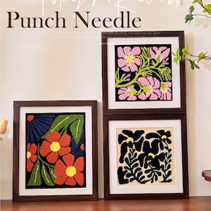 Könnte beinhalten: Drei gerahmte Punch-Needle-Kunstwerke. Die Kunstwerke zeigen florale Designs in verschiedenen Farben, darunter Rosa, Rot und Schwarz, vor einem dunklen Hintergrund. Die Rahmen sind dunkelbraun.