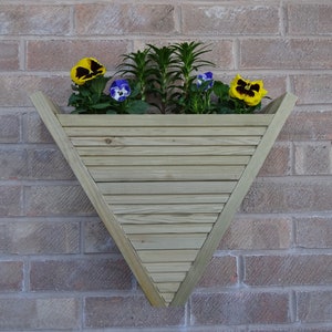 May include: A triangular wooden planter box with horizontal slats, mounted on a brick wall. The planter holds vibrant yellow and purple pansies and green foliage. The wooden planter is approximately 61 cm wide.
