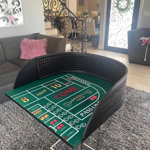 May include: A green felt craps table with a black leather border. The table has a standard craps layout with numbers, dice, and the words "Come", "Don't Pass Bar", and "Pass Line".