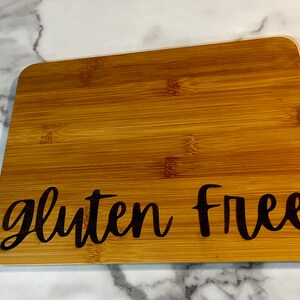Peut inclure: Une planche &agrave; d&eacute;couper en bambou brun avec le texte "gluten free" grav&eacute; en noir.