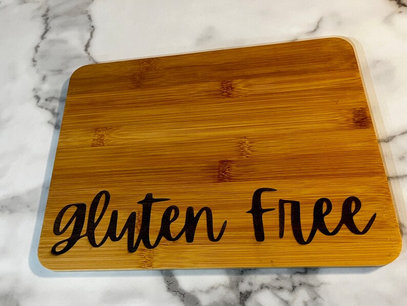 Peut inclure: Une planche &agrave; d&eacute;couper en bambou brun avec le texte "gluten free" grav&eacute; en noir.