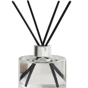 May include: A clear glass diffuser bottle with a silver cap and black diffuser sticks. The bottle is filled with a clear liquid.