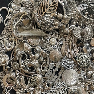 Puede incluir: Un mont&oacute;n grande de joyas plateadas, incluyendo collares, pulseras, pendientes, anillos y broches. Las joyas est&aacute;n dispuestas en un patr&oacute;n aleatorio, y algunas piezas se superponen.