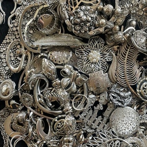 Puede incluir: Una gran colecci&oacute;n de joyas plateadas, incluyendo collares, pulseras, pendientes y broches. Las joyas est&aacute;n dispuestas en una pila, y muchas de las piezas est&aacute;n intrincadamente dise&ntilde;adas.