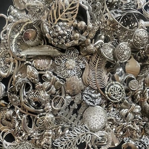 Puede incluir: Una gran colecci&oacute;n de piezas de joyer&iacute;a plateadas, incluyendo collares, pulseras, pendientes y broches. La joyer&iacute;a est&aacute; dispuesta en una pila ca&oacute;tica, con muchos dise&ntilde;os y estilos diferentes.