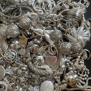 Puede incluir: Un mont&oacute;n grande de joyas plateadas, incluyendo collares, pulseras, aretes y dijes. Las joyas est&aacute;n dispuestas en un patr&oacute;n aleatorio, y algunas piezas se superponen. Las joyas est&aacute;n hechas de metal y tienen una variedad de dise&ntilde;os.