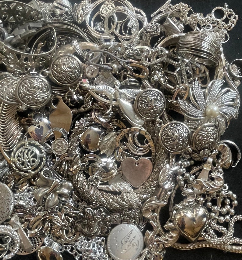 Puede incluir: Un mont&oacute;n grande de joyas plateadas, incluyendo collares, pulseras, aretes y dijes. Las joyas est&aacute;n dispuestas en un patr&oacute;n aleatorio, y algunas piezas se superponen. Las joyas est&aacute;n hechas de metal y tienen una variedad de dise&ntilde;os.
