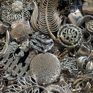 Puede incluir: Una gran colecci&oacute;n de piezas de joyer&iacute;a plateadas, que incluyen broches, collares y pendientes. La joyer&iacute;a presenta dise&ntilde;os intrincados, como flores, hojas y patrones geom&eacute;tricos.