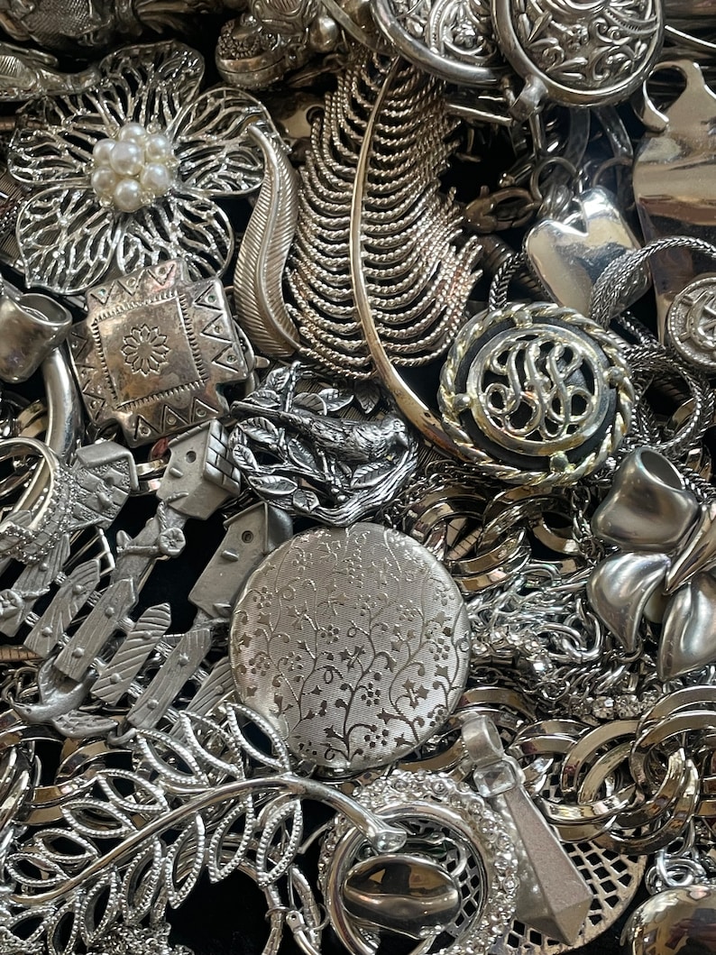 Puede incluir: Una gran colecci&oacute;n de piezas de joyer&iacute;a plateadas, que incluyen broches, collares y pendientes. La joyer&iacute;a presenta dise&ntilde;os intrincados, como flores, hojas y patrones geom&eacute;tricos.