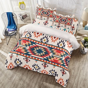 Puede incluir: Una funda nórdica blanca con un patrón geométrico colorido en tonos rojos, naranjas, azules y amarillos. El patrón recuerda a los diseños de los nativos americanos. La funda nórdica está en una cama con dos fundas de almohada a juego.