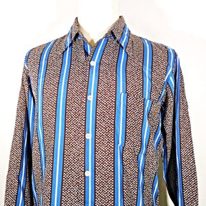 May include: A long-sleeved button-down shirt with a brown and blue striped pattern. The shirt has a pocket on the left side.