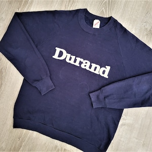 Op de afbeelding: Een donkerblauw sweatshirt met een wit "Durand" logo op de voorkant.