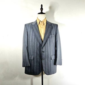 May include: A gray striped blazer with a single button closure. The blazer has a notched lapel and two flap pockets.