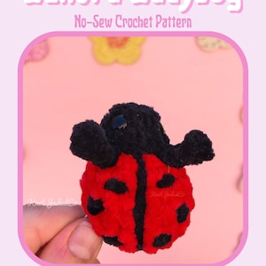 Può includere: Una coccinella di uncinetto rossa e nera con occhi neri e uno schema di uncinetto senza cuciture. Lo schema si chiama "Lenora Ladybug" ed è di Knot Jaded Co.