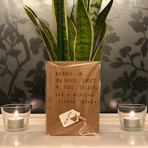 May include: A brown card with the text "Being a friend isn't a big thing it's a million little things" and a small tag that says "Bestie" on it.