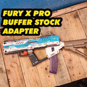 May include: A white and blue toy gun with a tan stock. The gun has a clear magazine and the text "Fury X Pro Buffer Stock Adapter" is written in yellow letters on a black background.