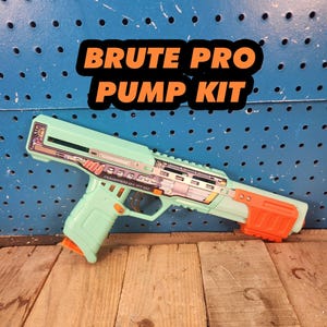 May include: A mint green and orange Brute Pro Pump Kit toy gun. The toy gun has a futuristic design with a long barrel and a handle. The text "BRUTE PRO PUMP KIT" is displayed in orange letters on a black background.