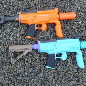 May include: Two toy water guns, one orange and one blue, with black grips and barrels. Both guns have the word "WATERBUSTER" printed on them.