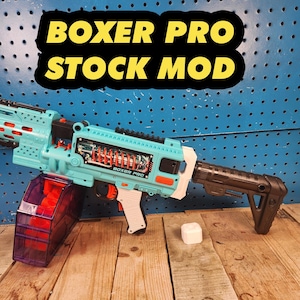 May include: A teal and orange Boxer Pro Stock Mod toy gun with a black stock and a clear purple magazine. The text "BOXER PRO STOCK MOD" is displayed in yellow letters on a black background.