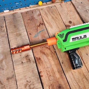 May include: A green and black toy gun with the word "MAULR" printed on the side. The gun has an orange barrel and a black handle. The text "DO NOT FIRE AT OBJECTS closer than 25 FT" is printed on the side.