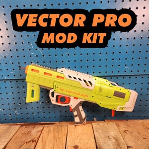 May include: A lime green and white Vector Pro Mod Kit toy gun with orange accents. The toy gun has the text "XF VECTOR PRO" printed on the side. The words "VECTOR PRO MOD KIT" are in orange text on a black background above the toy gun.