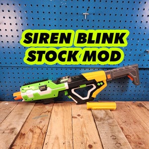 May include: A green and yellow toy gun with a black stock and a gray barrel. The gun has a black and white grip and a yellow and black barrel extension. The gun is labeled "SIREN BLINK STOCK MOD".