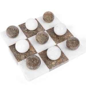 May include: A marble checkerboard game set with white and brown marble pieces. The board is made of white and brown marble squares.