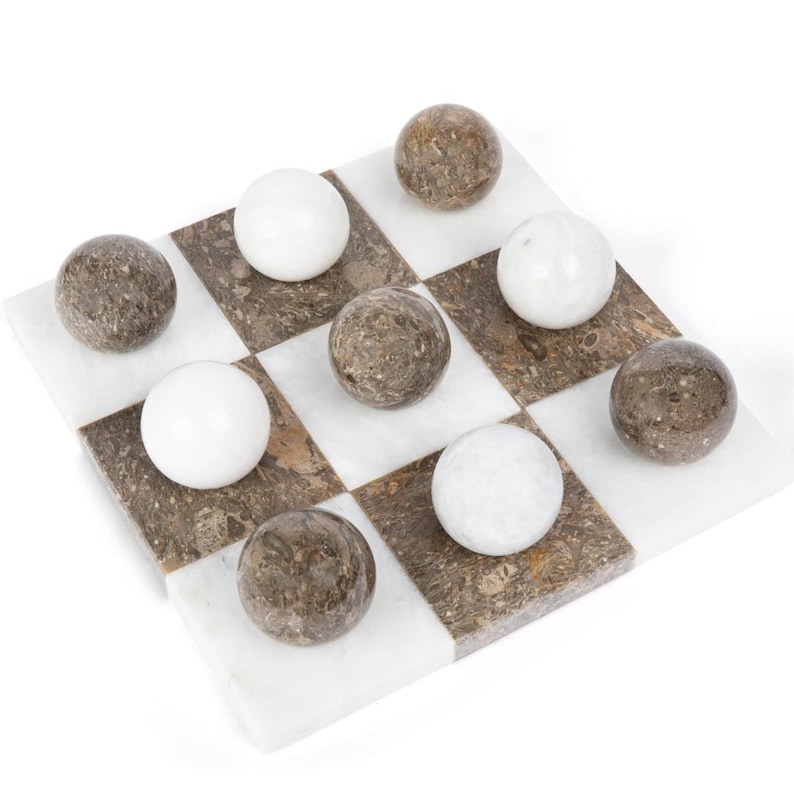 May include: A marble checkerboard game set with white and brown marble pieces. The board is made of white and brown marble squares.