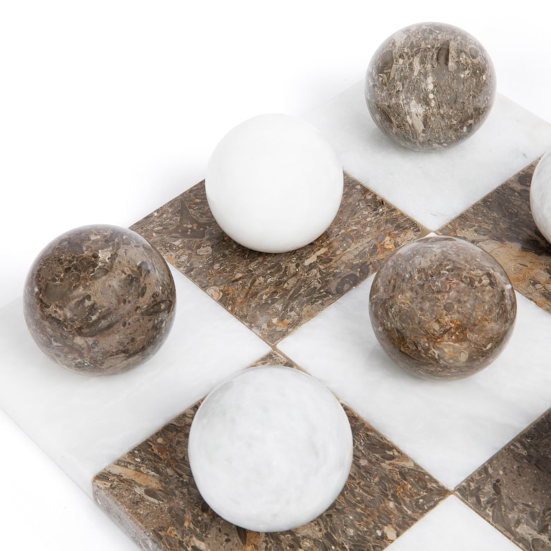 May include: A marble checkerboard game set with white and brown marble pieces. The checkerboard is made of white and brown marble squares.