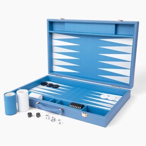 May include: Open blue backgammon set with white and black game pieces. The board is blue with white triangular points. Includes dice, dice cups, and a handle for carrying. The set is on a white background.