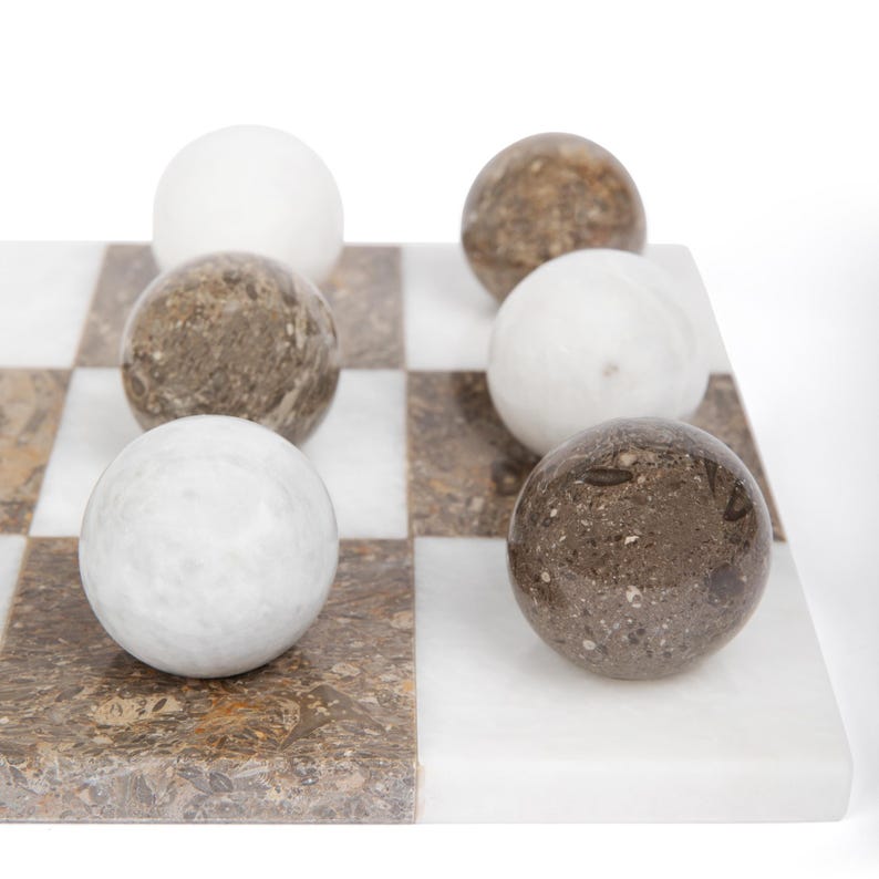 May include: A marble checkerboard game set with white and brown marble playing pieces. The checkerboard is made of white and brown marble squares.