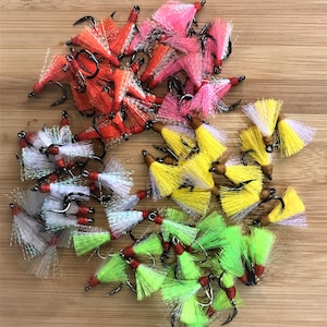May include: Assortment of colorful fly fishing lures with white, pink, red, yellow, and green feathers. The lures are tied on hooks with red and black accents.