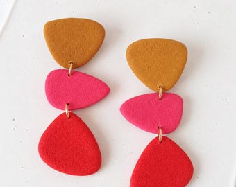 Pendientes coloridos de arcilla polimérica, colgantes geométricos, joyería llamativa en rosa y rojo.