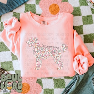 May include: A pink sweatshirt with a floral patterned silhouette of a dog and the text "Cockapoo Mom".