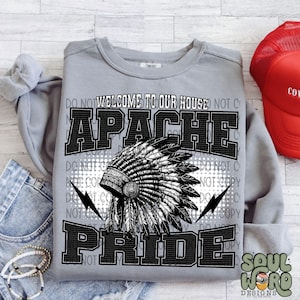 May include: A gray sweatshirt with a black and white graphic design featuring a Native American headdress and the text "Welcome to our house Apache Pride".
